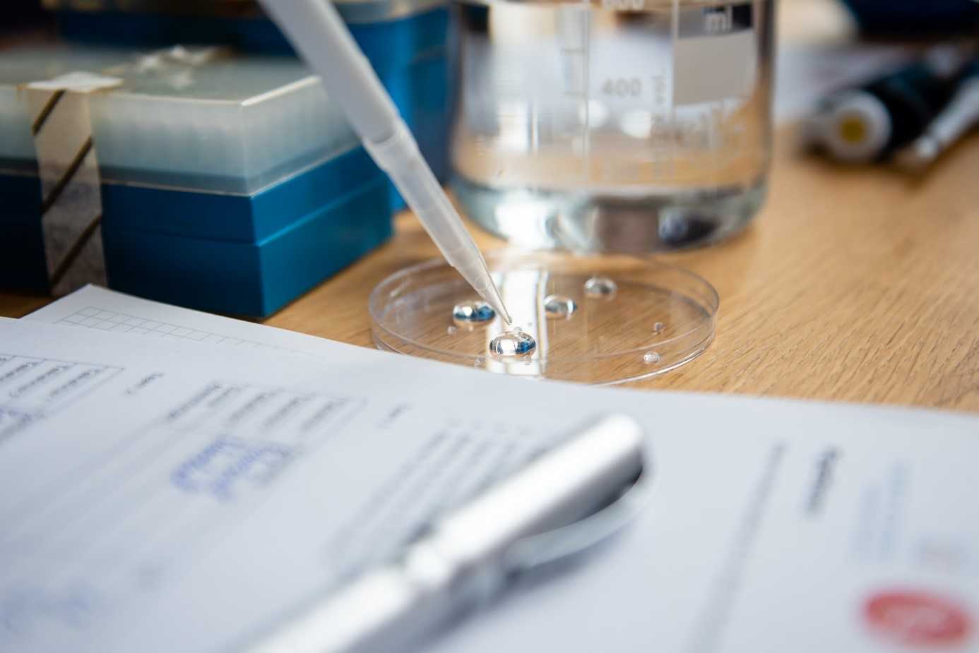 Das Foto zeigt eine Pipette und einen Reagenzbecher - eine Szene auf einem Chemielabortisch.