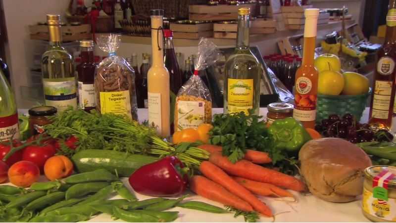 Das Foto zeigt einen voll beladenen Tisch mit regionalen Produkten - Gemüse, Teigwaren, Getränke, Öle, usw.